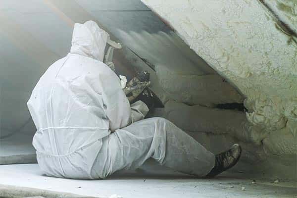 Spray foam insulation technician applying foam to attic.